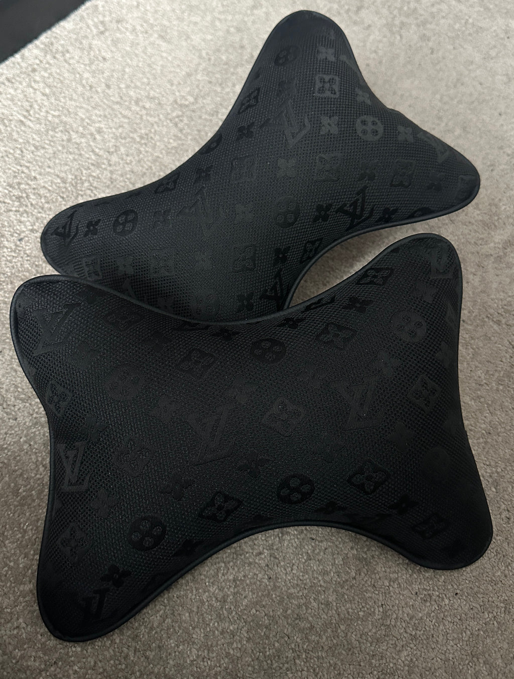 Black car headrest covers with a pattern on a gray surface